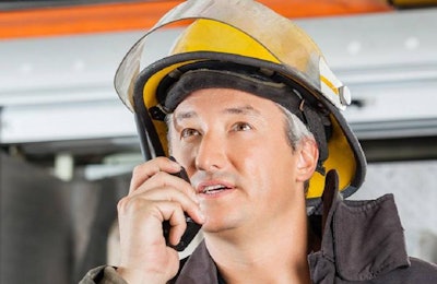 Mature fireman looking away while using walkie talkie at fire station