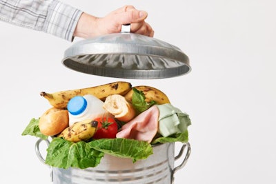 Hand Putting Lid On Garbage Can Full Of Waste Food