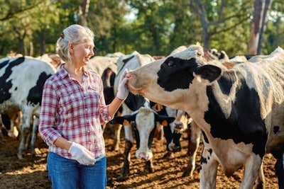 Happy Male Farmer On Cow Farm Around Herd