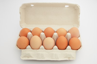 Uncooked eggs in packing on white background.