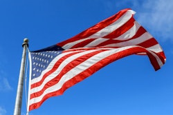 Usa Flag Waving Against Clear Blue Sky On Bright Sunny Day.