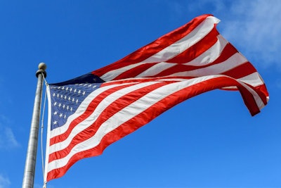 Usa Flag Waving Against Clear Blue Sky On Bright Sunny Day.
