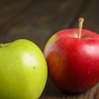Red And Green Apples Lie On A Wooden Table. There Are Two Apples