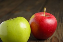 Red And Green Apples Lie On A Wooden Table. There Are Two Apples