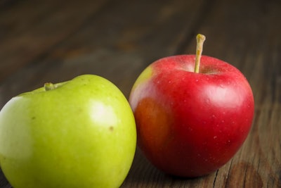 Red And Green Apples Lie On A Wooden Table. There Are Two Apples