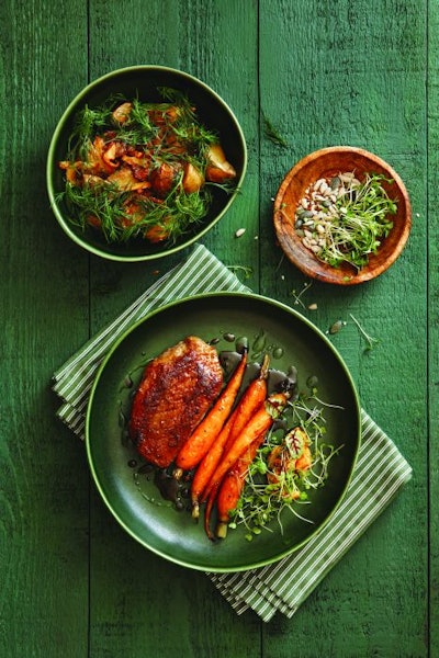 Roast duck breast with glazed carrot, carrot puree and microgreens. Roasted wild mushrooms and potatoes. Flat lay top-down composition on dark green background.
