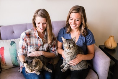 two women sitting with cats
