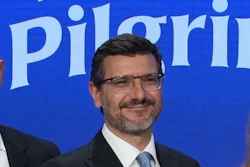 Professional man in glasses smiling in front of Pilgrim corporate backdrop
