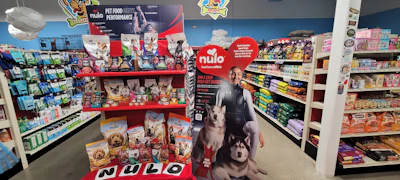 Nulo pet food retail display with red promotional stand, product shelves, and husky dog imagery in pet store aisle