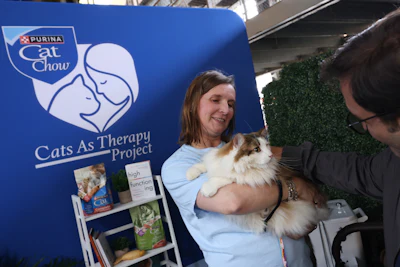 Woman holding a fluffy cat at Purina Cat Chow's Cats As Therapy Project promotional booth