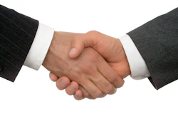 Two business professionals in formal attire shaking hands in agreement