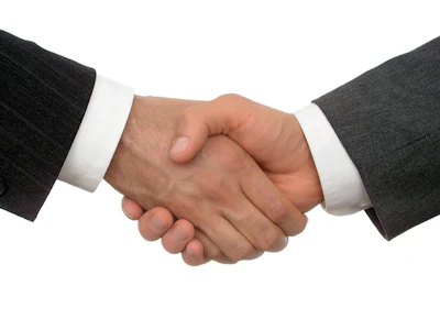 Two business professionals in formal attire shaking hands in agreement