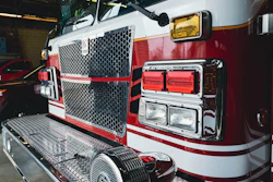 Red and white fire truck with hexagonal grille and emergency lights parked in garage