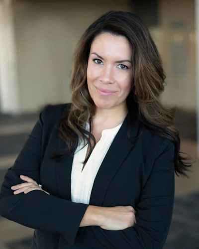 Professional woman in black blazer and white blouse with crossed arms in corporate portrait