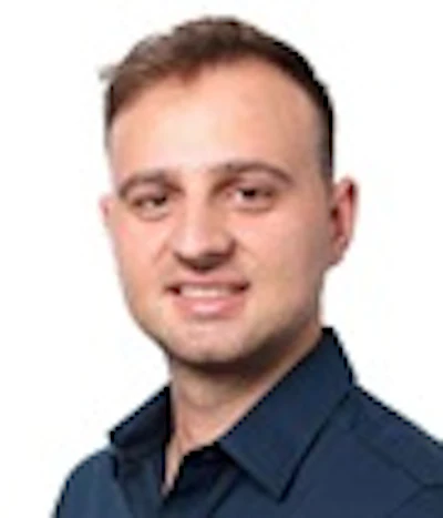 Professional headshot of a smiling man wearing glasses and a navy blue shirt