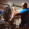 Worker operating industrial cutting machine with blue motor in workshop facility