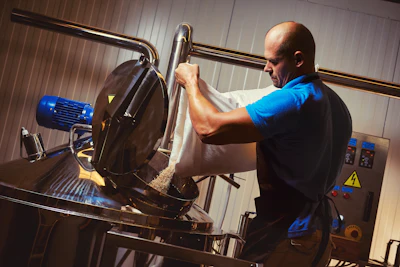 Worker operating industrial cutting machine with blue motor in workshop facility