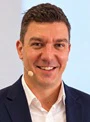 Professional headshot of a smiling man in dark blazer and white shirt