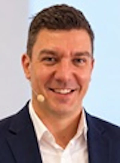 Professional headshot of a smiling man in dark blazer and white shirt