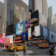 Times Square in New York City with tall buildings, digital billboards, yellow taxis, and crowds of pedestrians