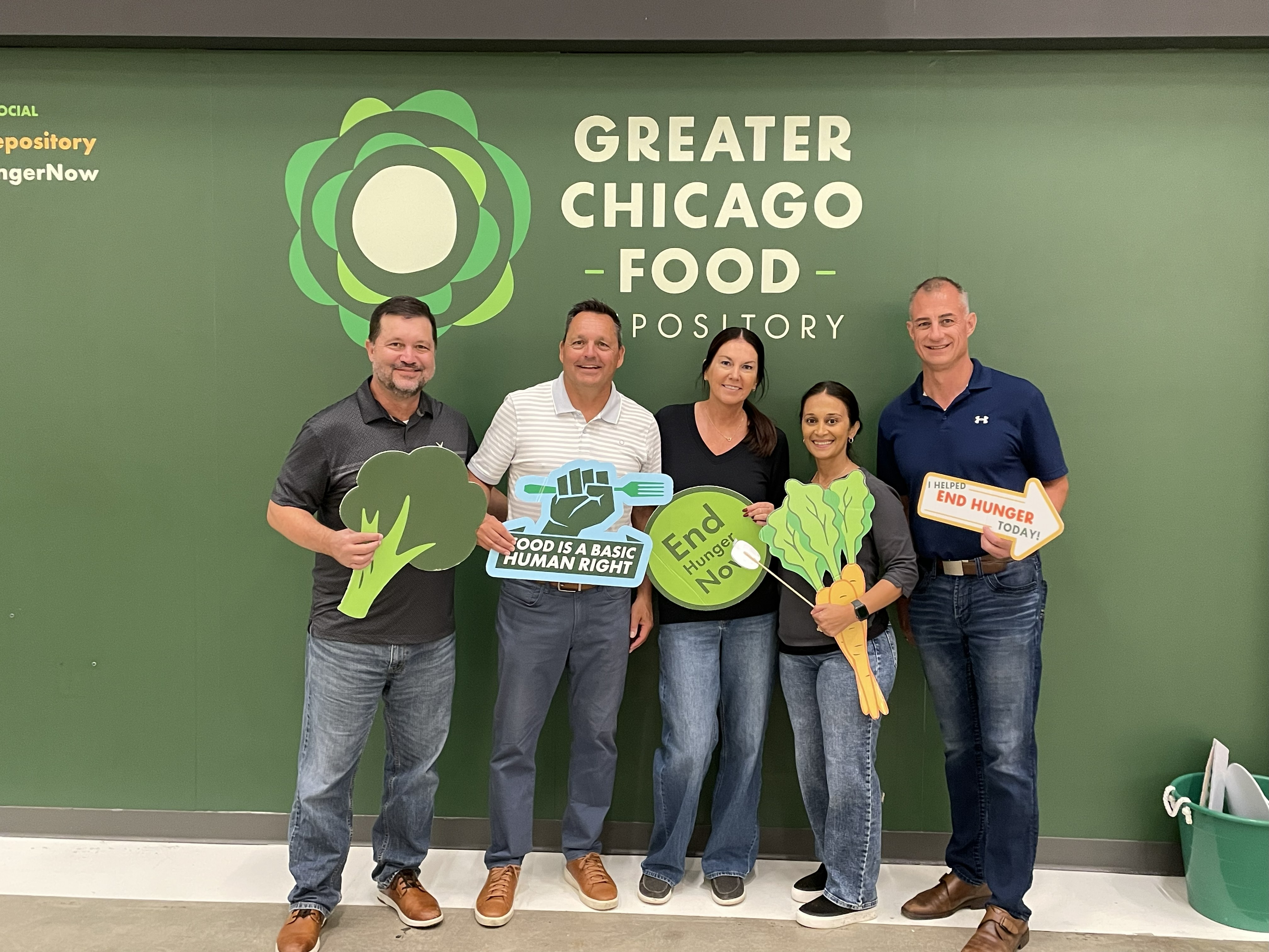 Five volunteers holding food advocacy signs at Greater Chicago Food Depository