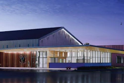 Modern waterfront building with pitched roof, wood and metal cladding, illuminated glass facade at dusk