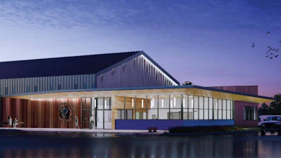 Modern waterfront building with pitched roof, wood and metal cladding, illuminated glass facade at dusk