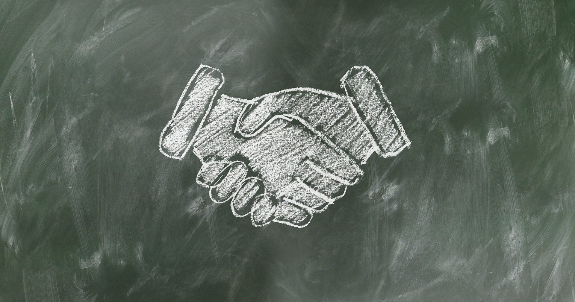 White chalk handshake illustration drawn on a dark green chalkboard background