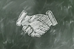 White chalk handshake illustration drawn on a dark green chalkboard background