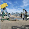 Industrial concrete mixer and conveyor system with yellow hopper and green support frame at outdoor facility